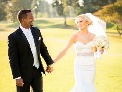 Angela Unkrich and Alfonso Ribeiro are in their wedding dress, holding hands, looking at each other.